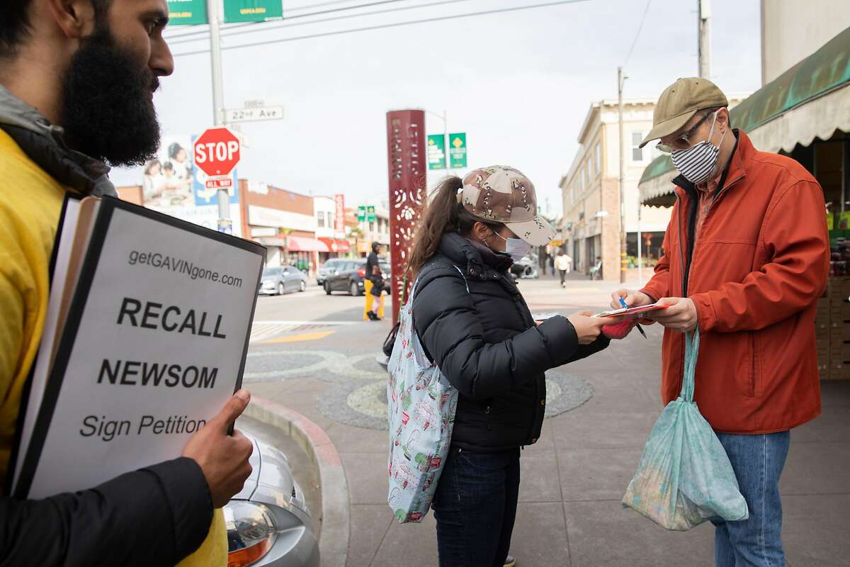 Carlo Mastrogiacomo of San Francisco signs a petition to recall Gavin Newsom outside the 22nd & Irving Market in San Francisco on March 2, 2021.