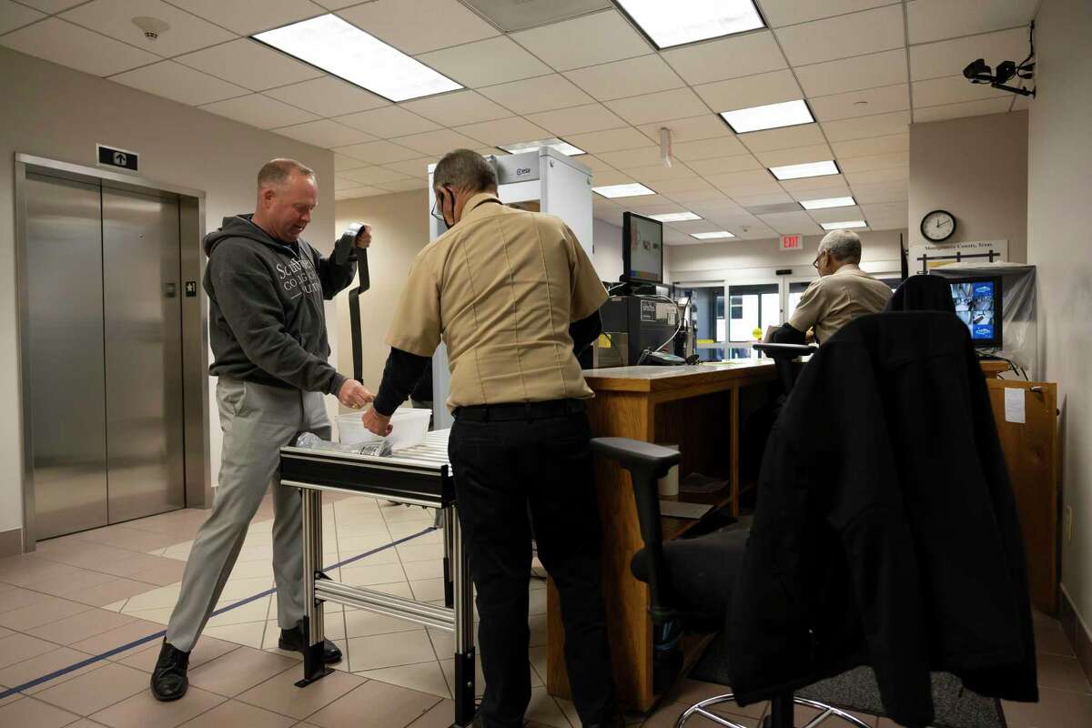 A visitor unloads his checked items after going through security at the Lee G. Alworth Building, Thursday, March 18, 2021, in Conroe. In-person jury duty cases have been held inside the courtrooms despite the ongoing COVID-19 pandemic.