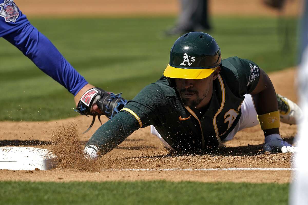 A’s left fielder Tony Kemp, who had been hit by a pitch, dives back safely into first base on a second-inning pick-off attempt by Cubs starter Kyle Davies. Kemp was 0-2 in the game.