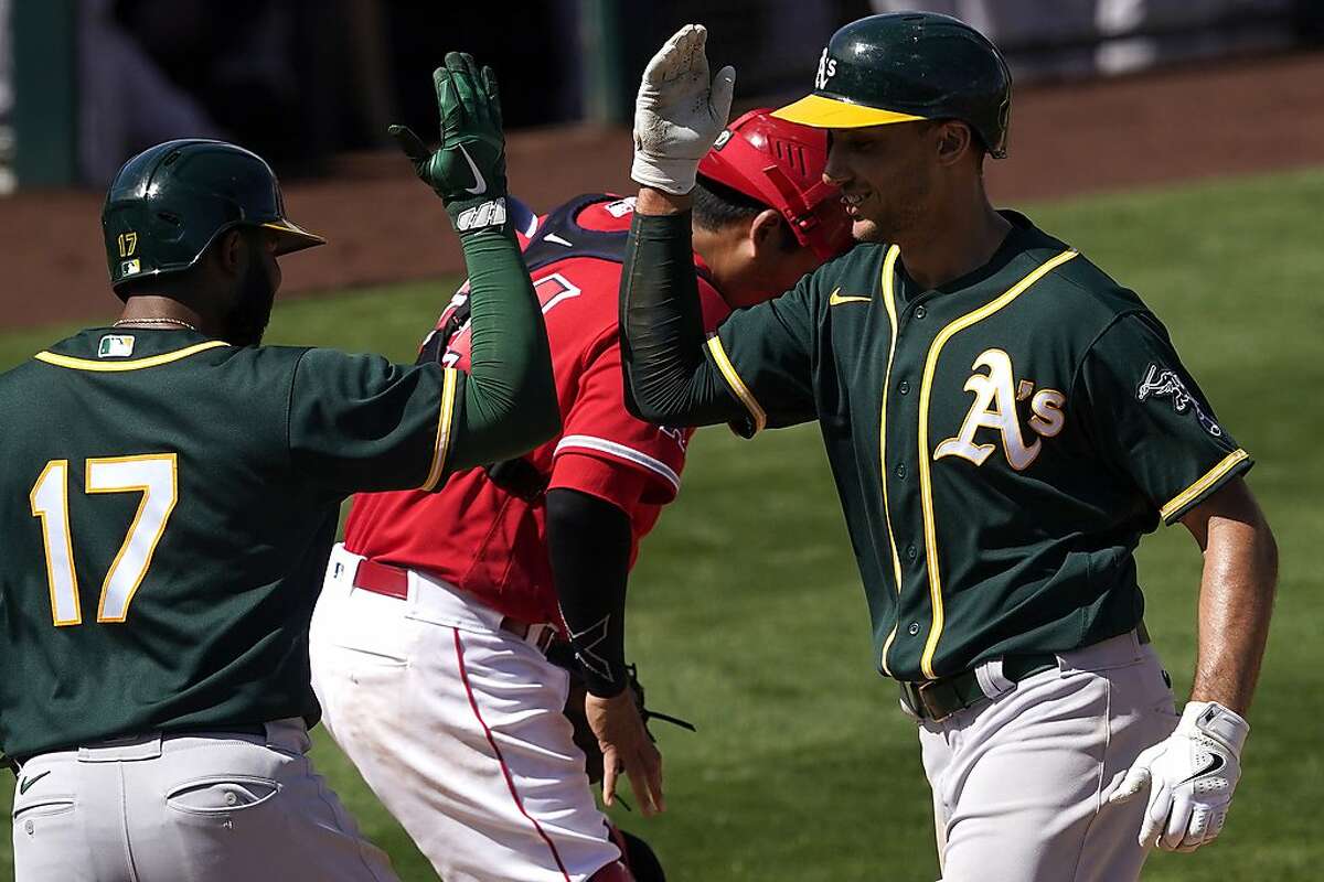Oakland Athletics' Matt Olson high fives teammate Elvis Andrus (17) after hitting a two run home run against the Los Angeles Angels during the third inning of a spring training baseball game, Saturday, March 20, 2021, in Tempe, Ariz. (AP Photo/Matt York)