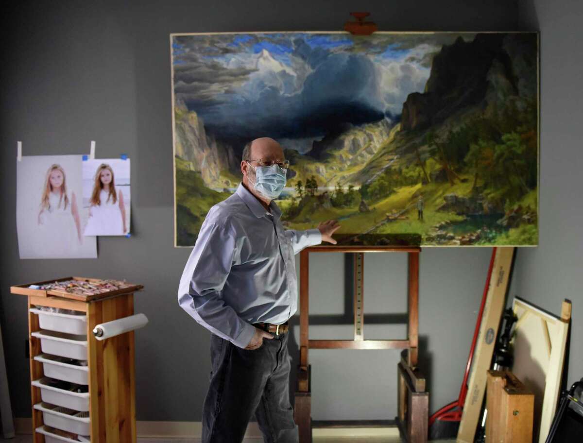 Artist Jeff Damberg shows his painting "Before a Storm in the Rocky Mountains" in his apartment at Agnes Morley Heights in Greenwich, Conn. Wednesday, March 10, 2021. Damberg has had a successful career in the arts as a painter, copyist, and restorationist, despite setbacks in school and many aspects of daily life caused by his dyslexia.