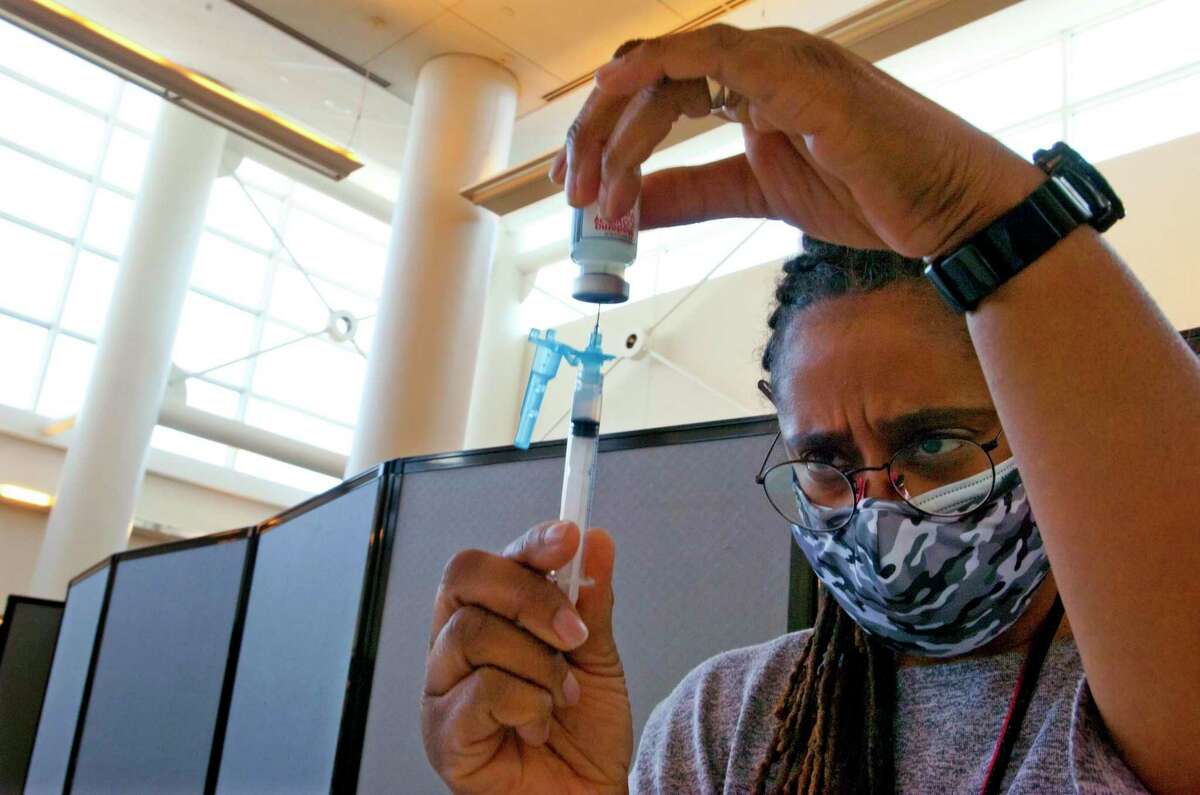 Darleen Hoffler, of the Norwalk Health Department, prepares as syringe during a mass vaccination clinic at Brien McMahon High School in Norwalk on Saturday.