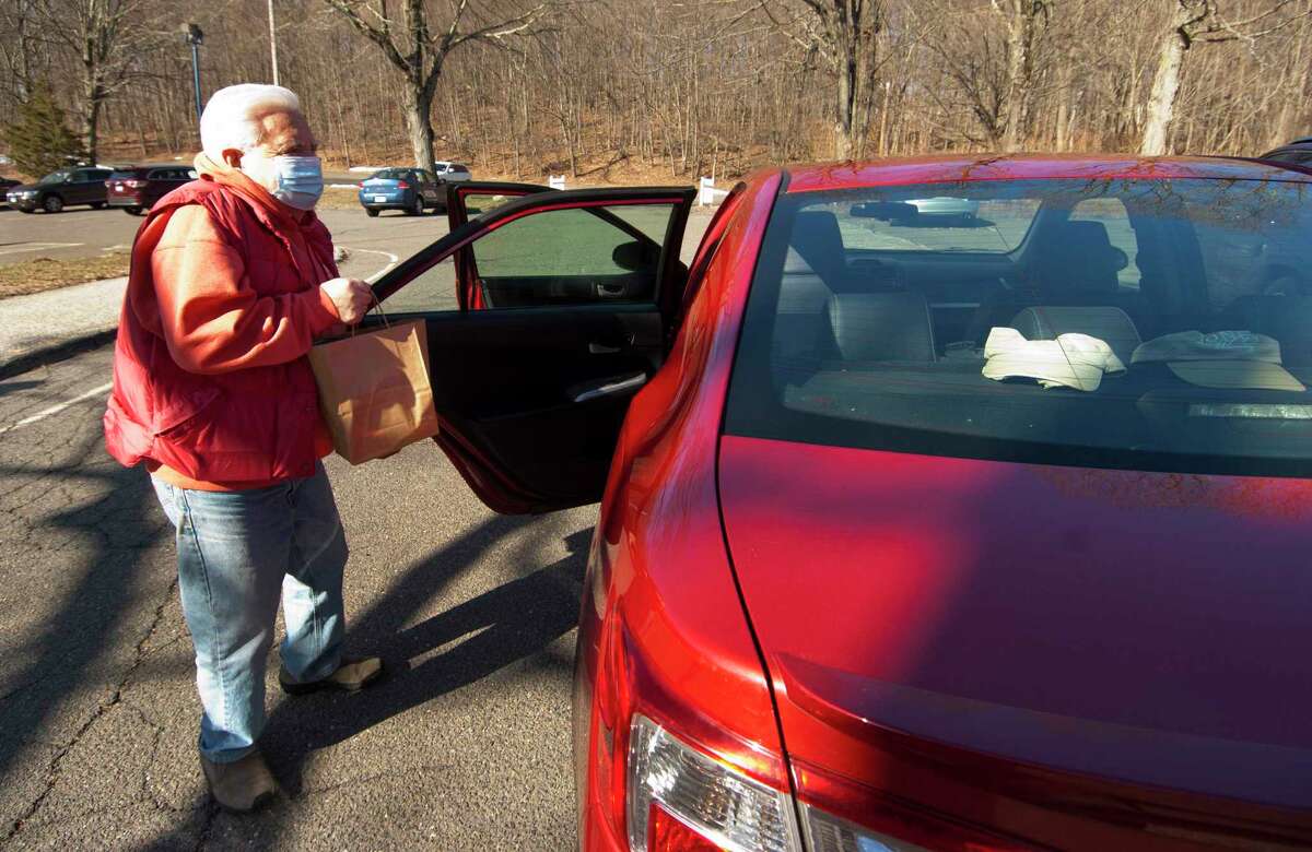 Bob Sembera donates a bag of food during Huntington Congregational Church's drive-thru food collection in Shelton, Conn., on Saturday Mar. 20, 2021. The collected food goes to the Valley Food Bank at Spooner House.