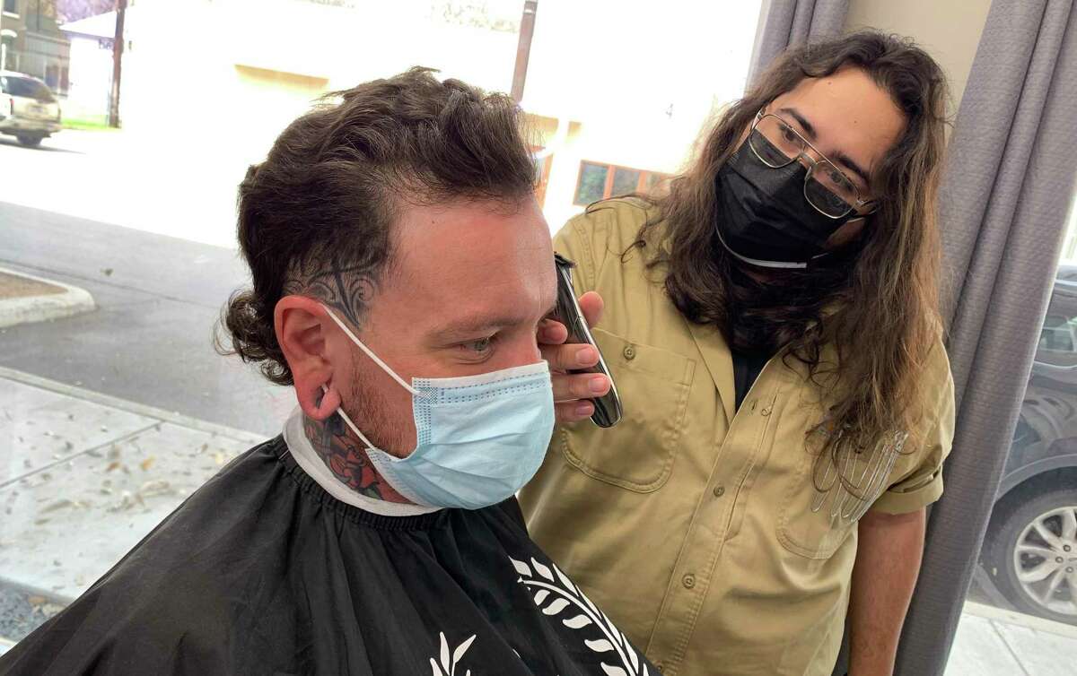 Barber Jonné Jasso, right, touches up the mullet of fellow barber Sebastian Thompson at Pinstripes Classic Barber Shop in San Antonio.