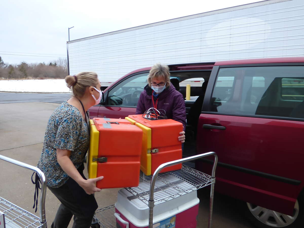 Keri Carlson and Nancy Fortin load heated food containers up for Meals on Wheels delivery.