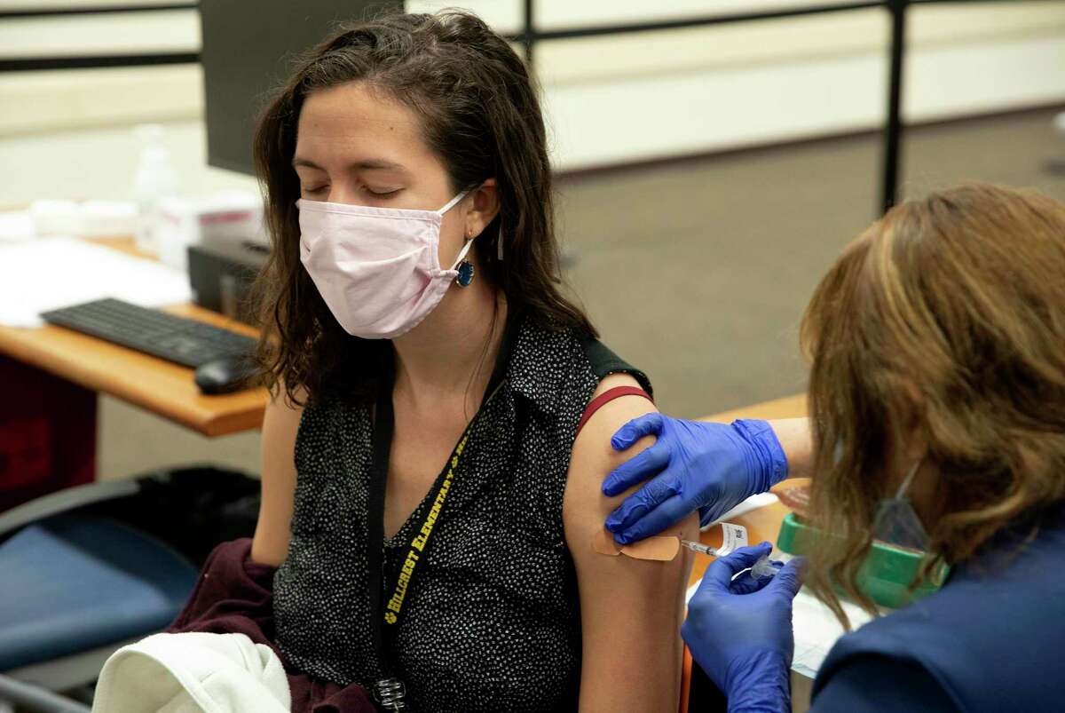 Anna Vuich, a first grade teacher in SAISD, receives her vaccine Monday from a University Health medical assistant. About 5,000 of the district’s employees are expected to receive their vaccines this week at Wonderland of the Americas Mall.