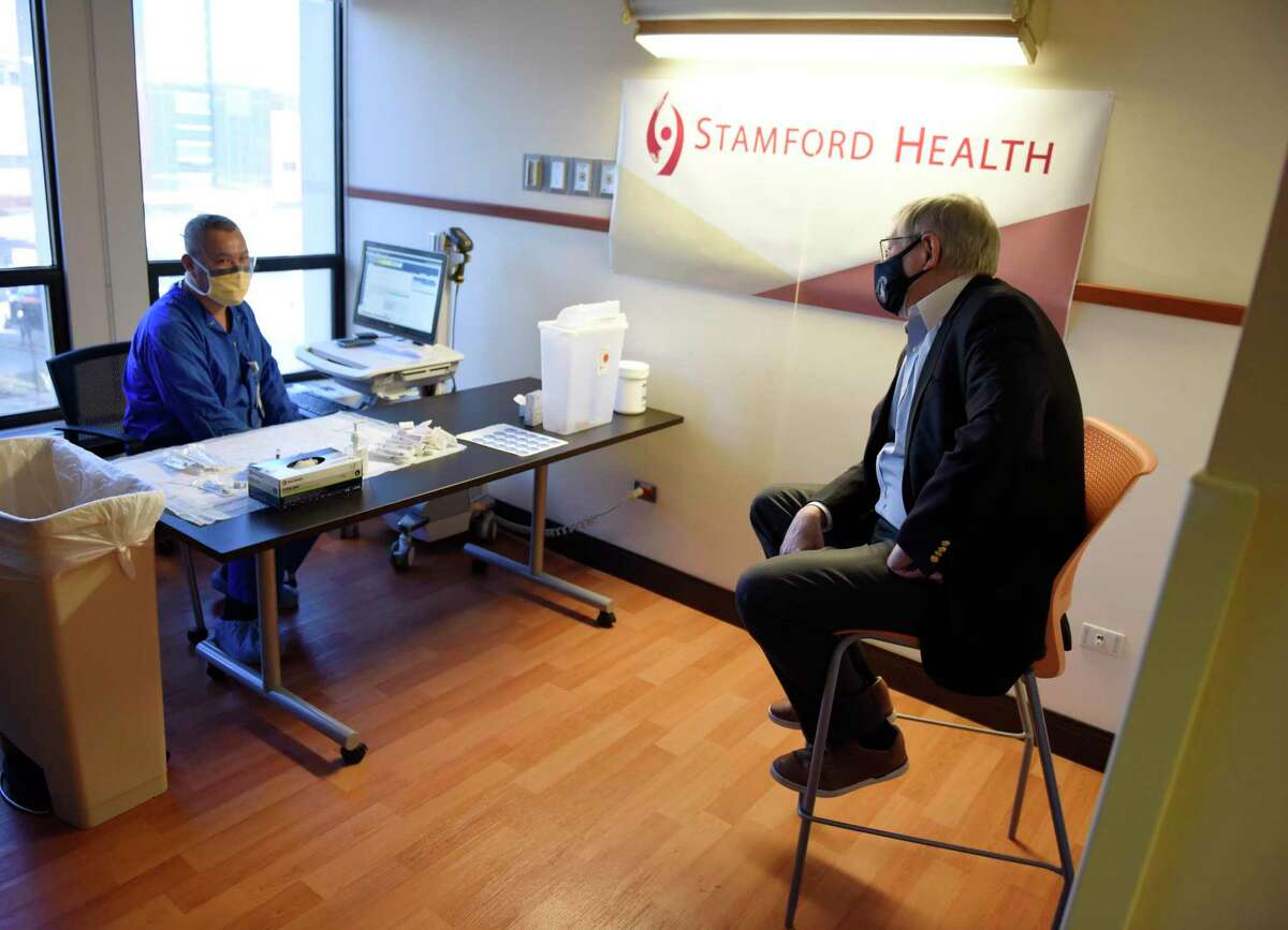 Stamford Mayor David Martin speaks with Cecil Chan, RN, before receiving his first COVID-19 vaccine at Stamford Hospital in Stamford, Conn. Monday, March 8, 2021.