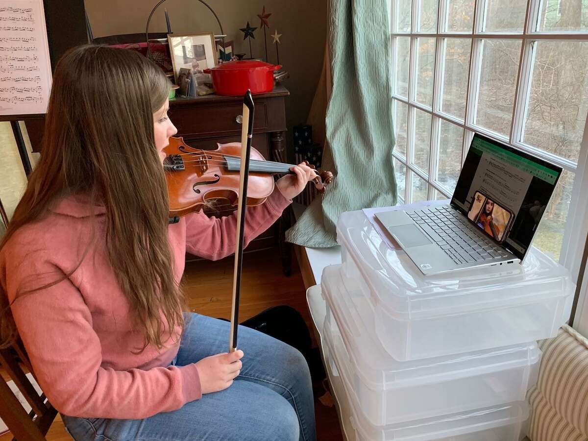 A Ridgefield High School student guides her fifth-grade violin mentee through a lesson over FaceTime.
