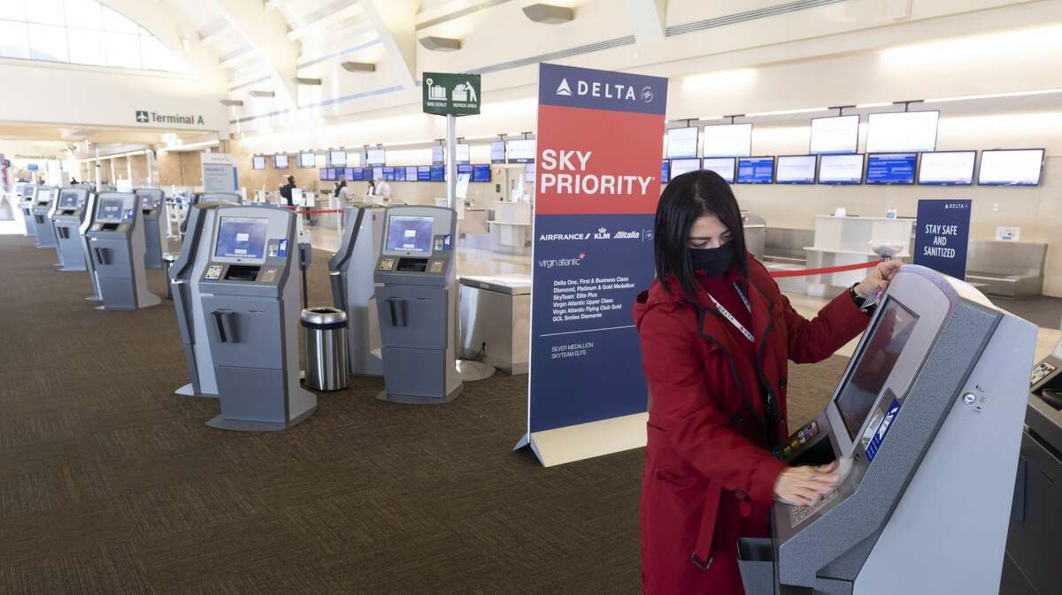 SANTA ANA, CA - JANUARY 26: A Delta Airlines agent sanitizes ticketing kiosks at John Wayne Airport in Santa Ana, CA on Tuesday, January 26, 2021. Passenger traffic at JWA was down more than 60% in 2020 due to the pandemic. (Photo by Paul Bersebach/MediaNews Group/Orange County Register via Getty Images)