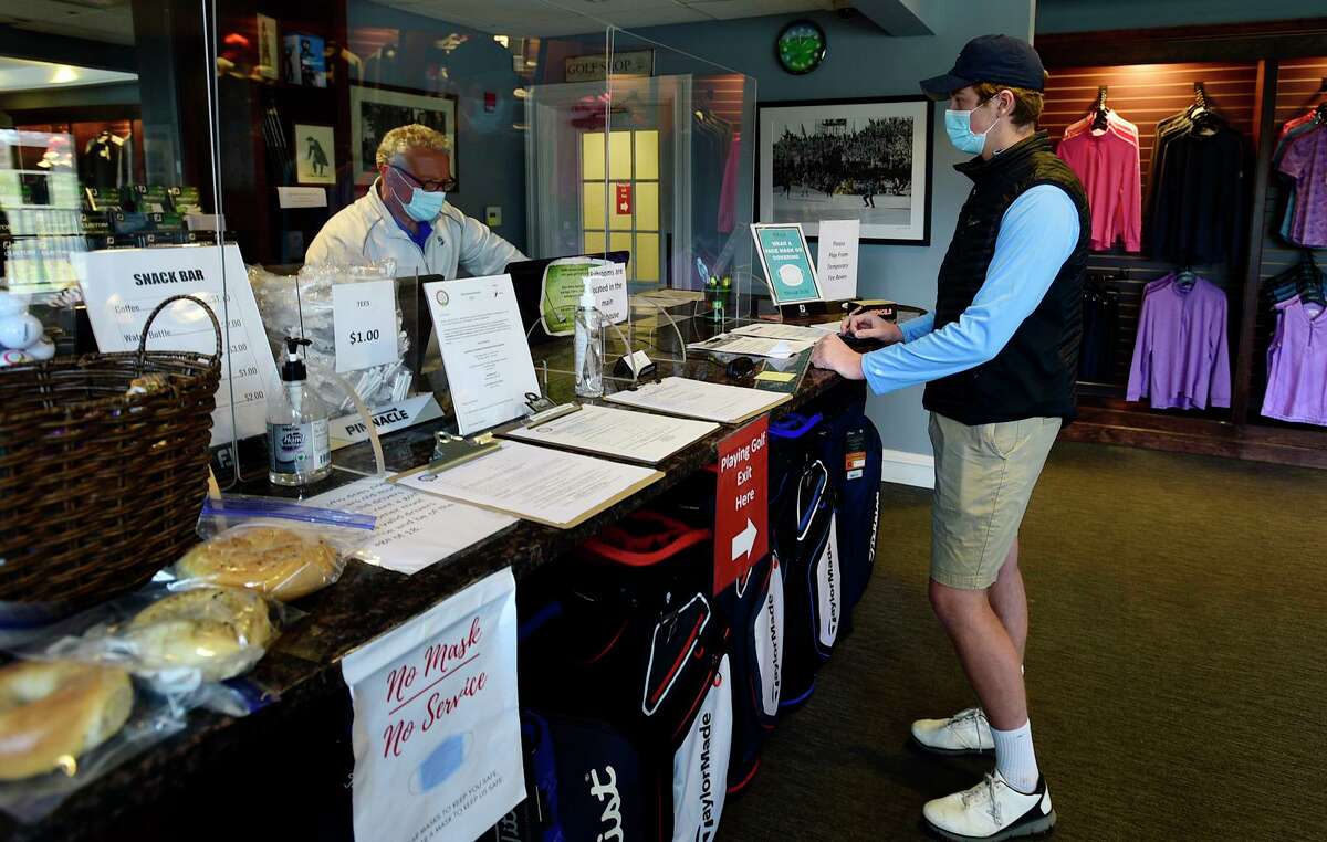 Golfers including William Winalski of New Canaan, right, checks in for a round at the Oak Hill Golf course Wednesday, March 24, 2021, in Norwalk, Conn. Oak Hills is performing well financially due in part to COVID.