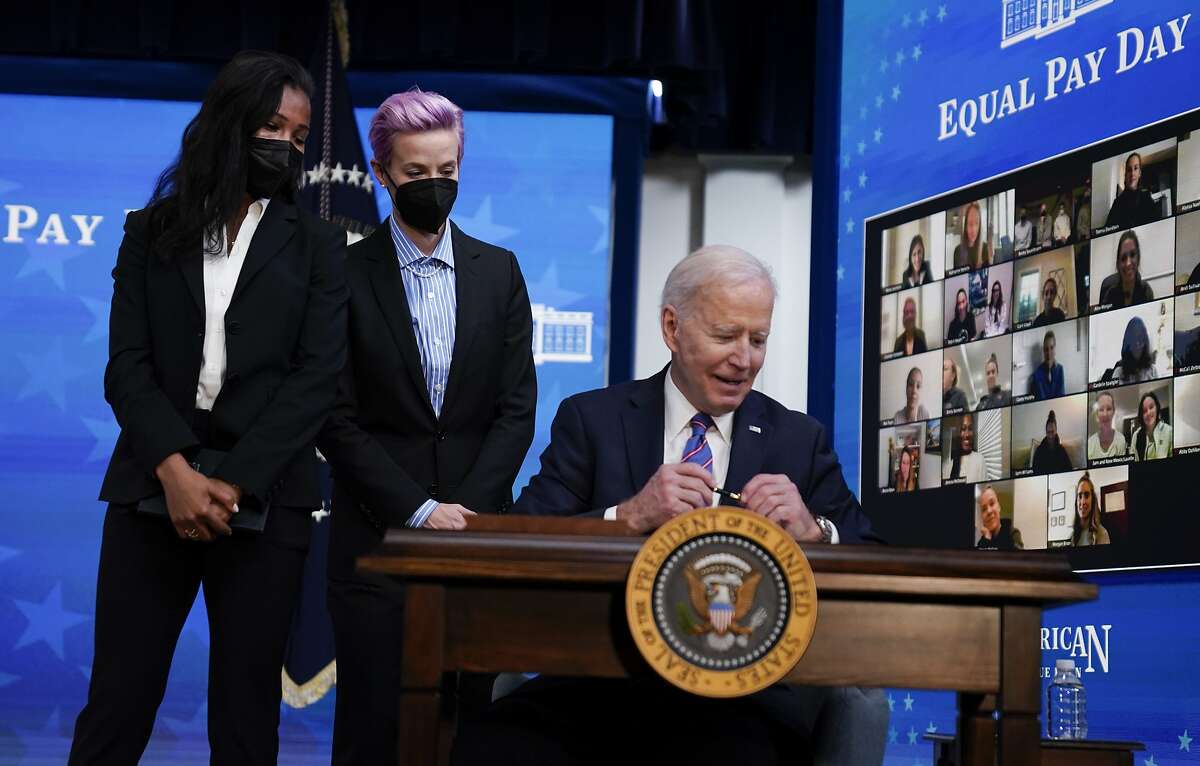 President Biden signs a proclamation recognizing Equal Pay Day as U.S. Soccer’s Margaret Purce and Megan Rapinoe watch.