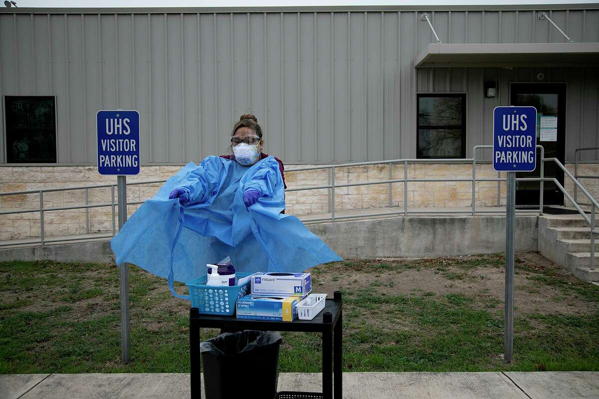 Medical Assistant Crystal Casias removes her gown after testing a woman, who remained in her car, for COVID-19 at University Health’s Southwest ISD school-based clinic in San Antonio on Wednesday, Feb. 10, 2021.