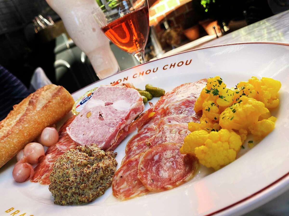A housemade charcuterie sampler includes, from left, saucisson rouge, country paté with pork, rabbit loin and pistachios wrapped in bacon and a sausage called rosette de Lyon, along with pickled onions, cornichons, moutarde de Meaux and pickled cauliflower at Brasserie Mon Chou Chou.