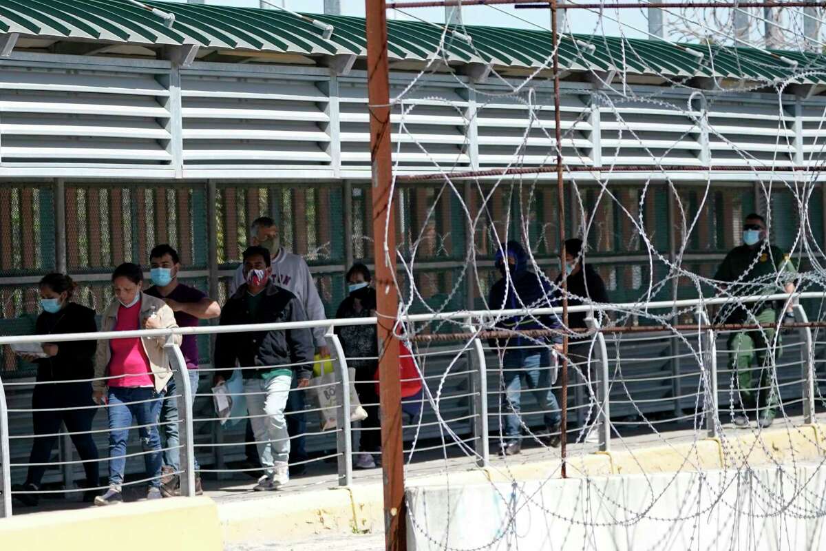 Migrants who were caught trying to sneak into the United States walk across the McAllen-Hidalgo International Bridge point of entry as they are deported to Reynosa, Mexico, Thursday, March 18, 2021, in Hidalgo, Texas. A surge of migrants on the Southwest border has the Biden administration on the defensive. The head of Homeland Security acknowledged the severity of the problem Tuesday but insisted it's under control and said he won't revive a Trump-era practice of immediately expelling teens and children. (AP Photo/Julio Cortez)