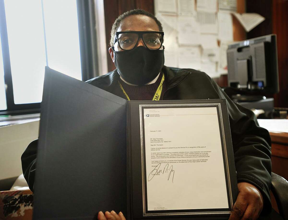 Bridgeport Postmaster Gary Thompson holds a signed letter from the postmaster general celebrating his 50 years of service with the Postal Service in Bridgeport, Conn. on Wednesday, March 24, 2021.