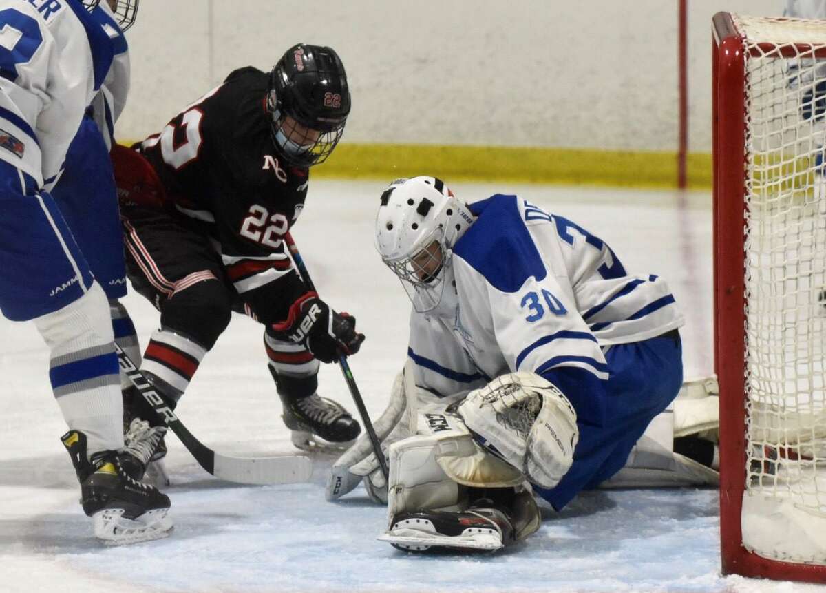 Darien goalie Teddy DeBeradinis makes a save against New Canaan’s Carter Spain (22) during the FCIAC boys ice hockey semifinals at the Darien Ice House on Thursday.