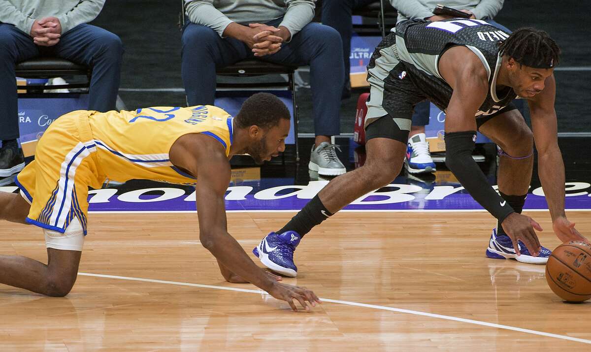 Golden State Warriors forward Andrew Wiggins (22) and Sacramento Kings guard Buddy Hield (24) chase the ball during the first quarter of an NBA basketball game in Sacramento, Calif., Thursday, March 25, 2021. (AP Photo/Randall Benton)