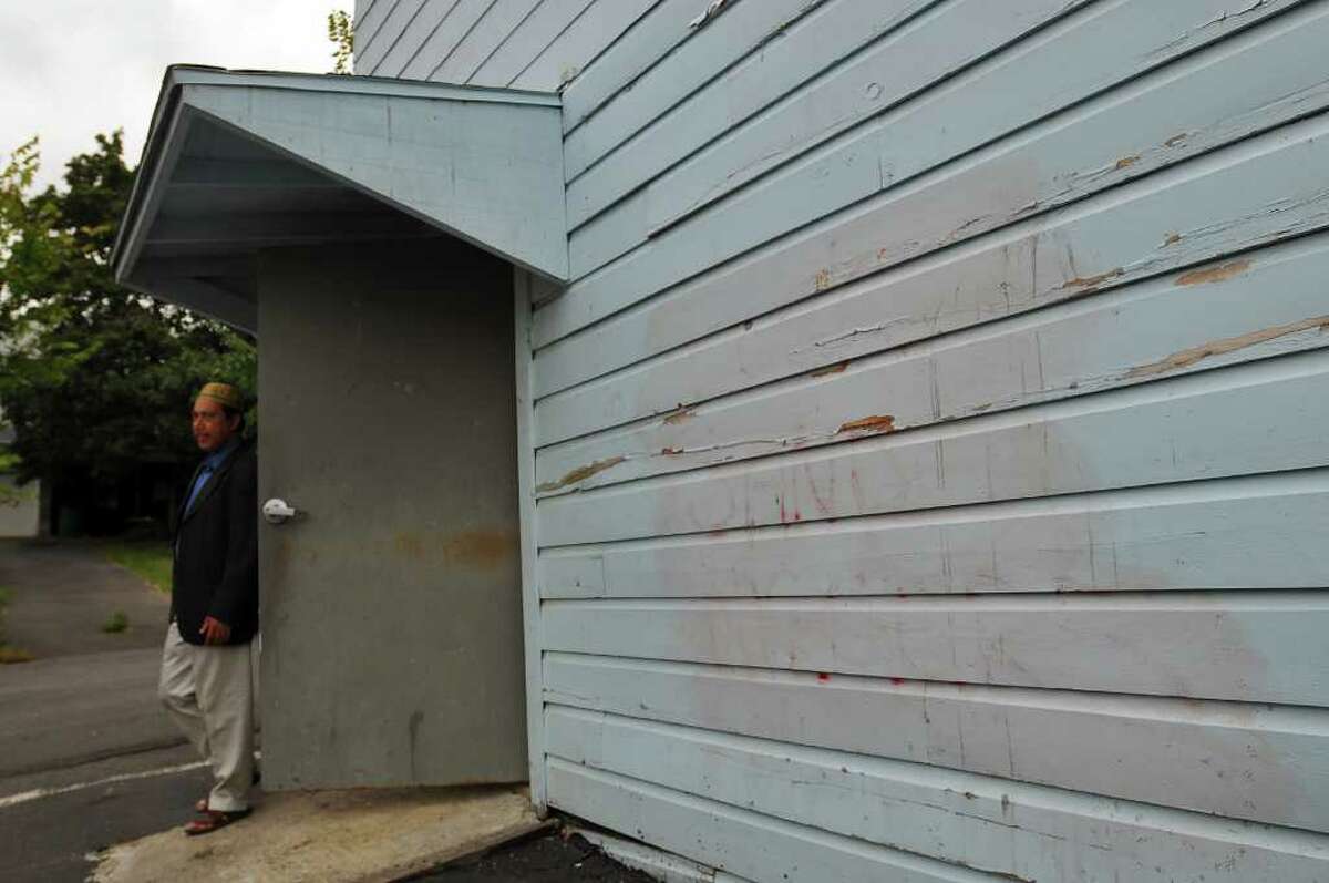 Jalal Uddin, president of the Hudson Islamic Center, stands behind the center where graffiti defaced the building. It can be seen mostly erased to the right of the door. ( Philip Kamrass / Times Union )
