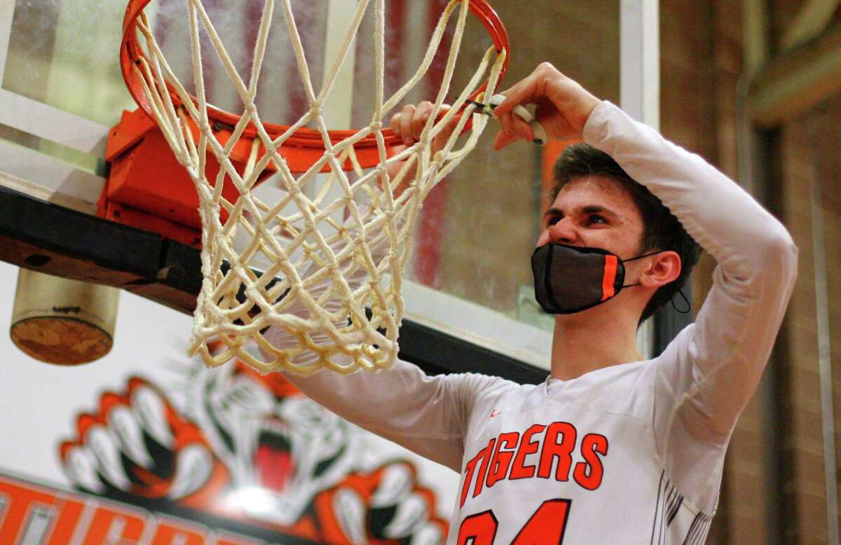 Ridgefield's Amos Grey cuts off a piece of the net after the team defeated FCIAC championship boys basketball game action in Ridgefield, Conn., on Friday March 27, 2021.