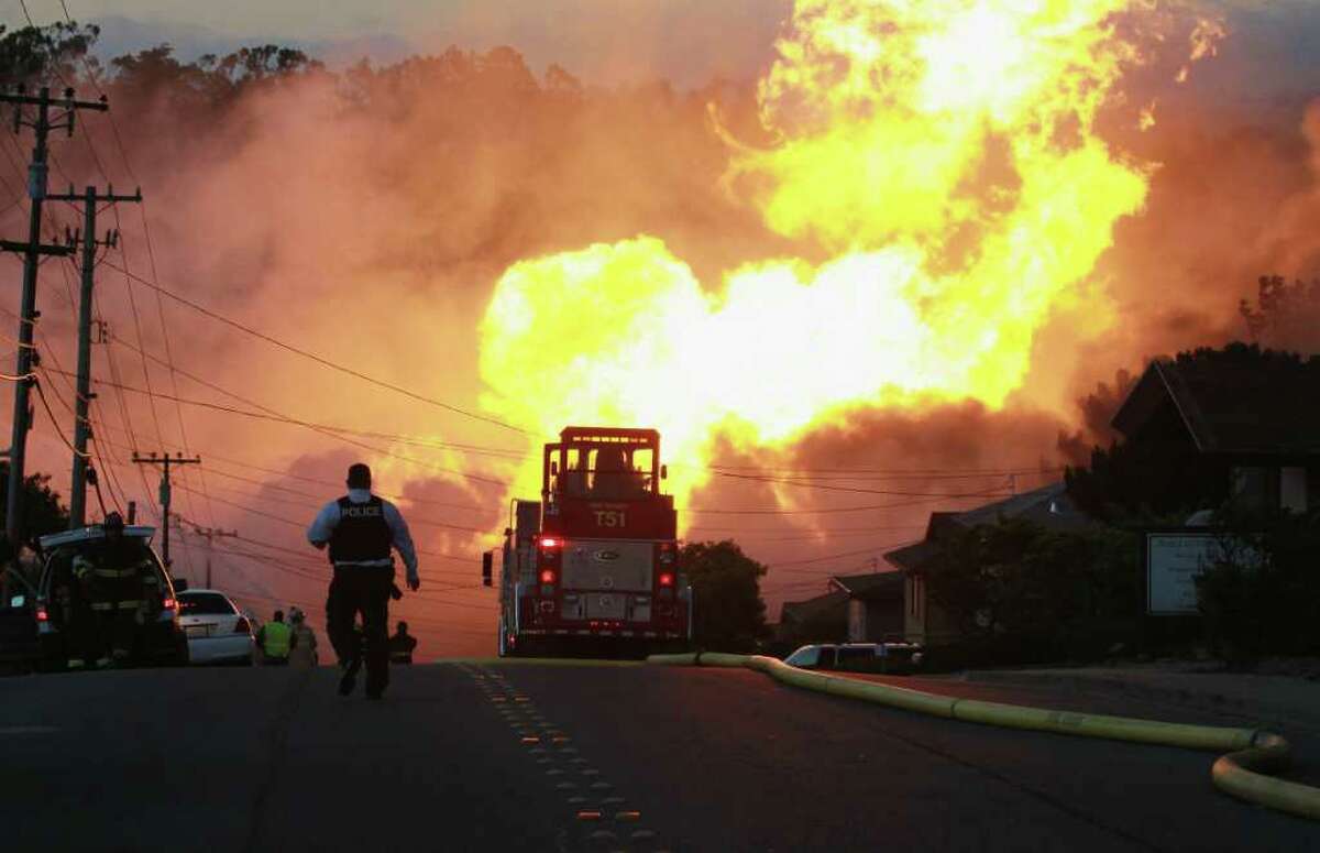 SAN BRUNO, CA - SEPTEMBER 09: A law enforcement official runs towards a massive fire in a residential neighborhood September 9, 2010 in San Bruno, California. A massive explosion rocked a neighborhood near San Francisco International Airport. (Photo by Justin Sullivan/Getty Images)