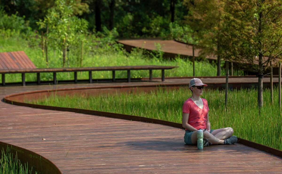 A woman meditates at Hines Lake and the new Eastern Glades at Memorial Park on September 11, 2020 in Houston.
