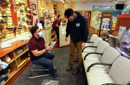 Matt Arciuolo II, helps customer Jonathan Fava at Arciuolo's Shoes in Milford, Conn., on Friday March 26, 2021. The business will be celebrating its 100th anniversary in August.