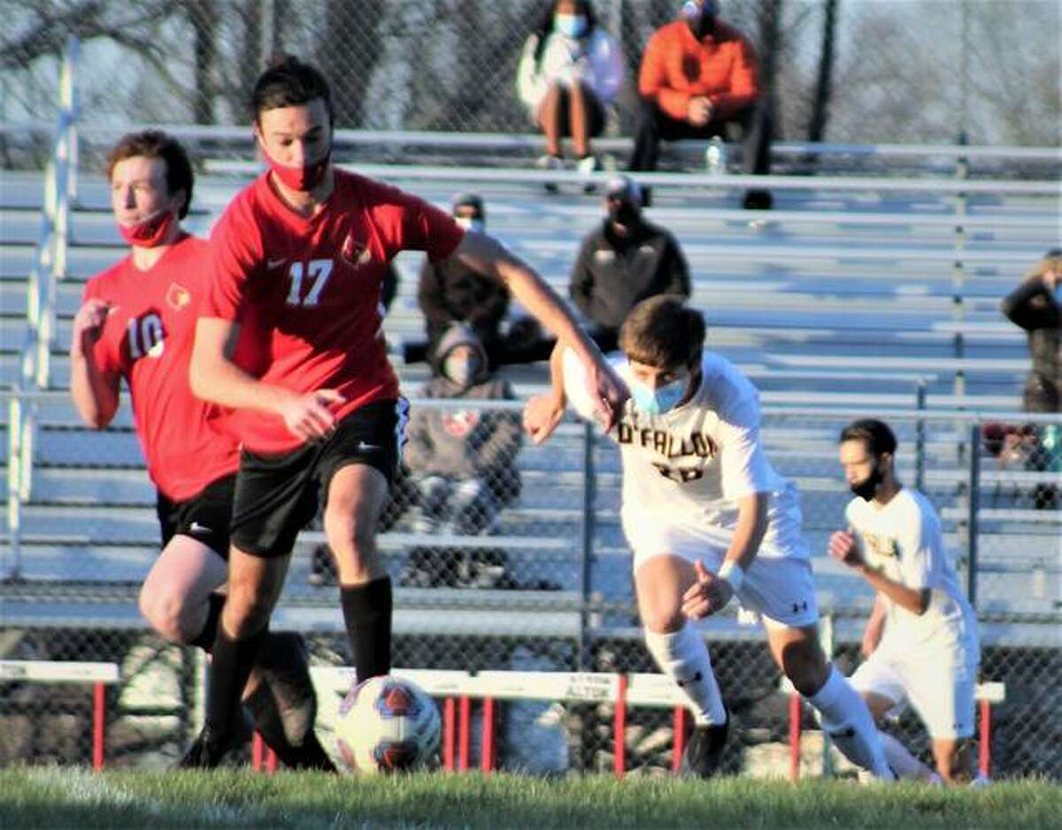Chase Ely of Alton (17) dribbles upfield and is pursued by O’Fallon’s Nolan Kumming (20) Monday at Alton High.