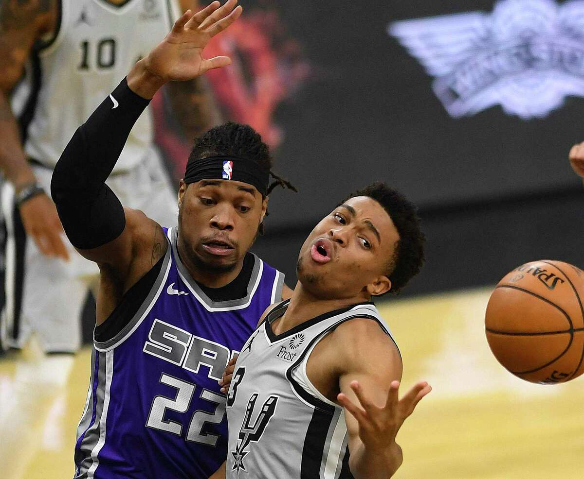 Keldon Johnson of the San Antonio Spurs, right, reaches for the ball as Richaun Holmes of Sacramento defends during NBA action in the AT&T Center on Monday, March 29, 2021.