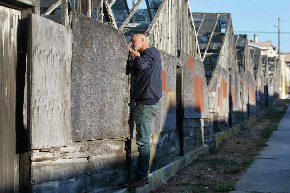 David Gabriner peeks inside a decaying greenhouse in the Portola district of San Francisco in 2015. Eighteen glass and wood greenhouses have fallen in disrepair since 1992 when the business shut down. Gabriner is co-founder of an organization that is hoping to acquire the property and restore the site.