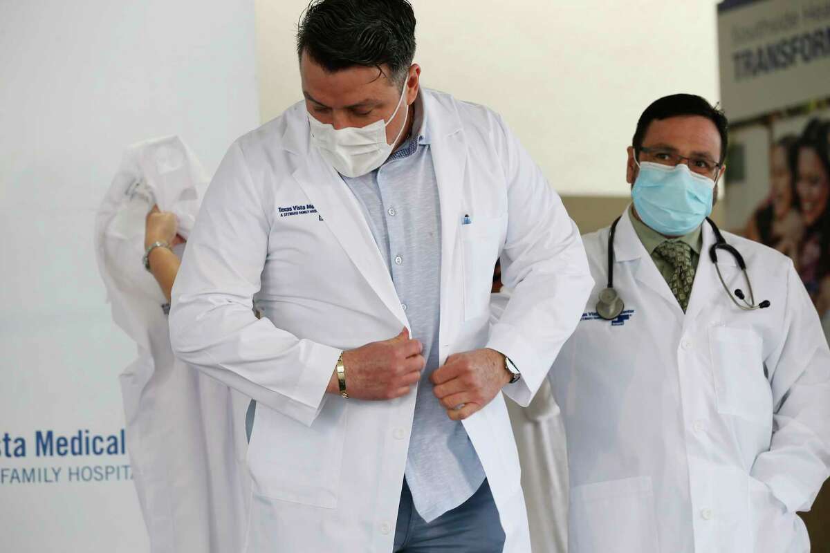 Internal Medicine Dr. Manuel Estrada, left, tries on a new gown as Family Medicine Dr. Edgardo Benavides looks on during a ceremony for the rebranding of the former Southwest General Hospital as Texas Vista Medical Center, Tuesday, March 30, 2021. The hospital opened 1979 and Steward Health Care, a physician-owned company, bought it in 2017. They also announced a new community program, Health Horizons.