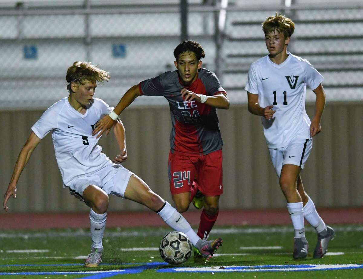 Julian Sanchez of LEE, middle, drives the ball enroute to a goal as Cade Dougan (5) and Thompson Schmeil (11) of Austin Vandegrift defend during Area Playoff action at Comalander Stadium on Tuesday, March 30, 2021.
