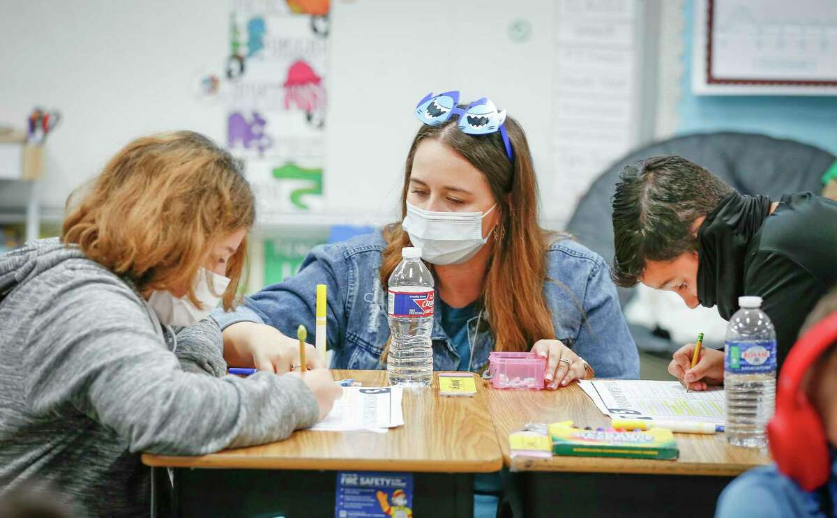 Kendalyn Weber (left) and Isaac Navan work with teacher Elizabeth Harlan at Deer Park Elementary School, where 99 percent of students have returned to campus, Tuesday, March 30, 2021, in Deer Park.