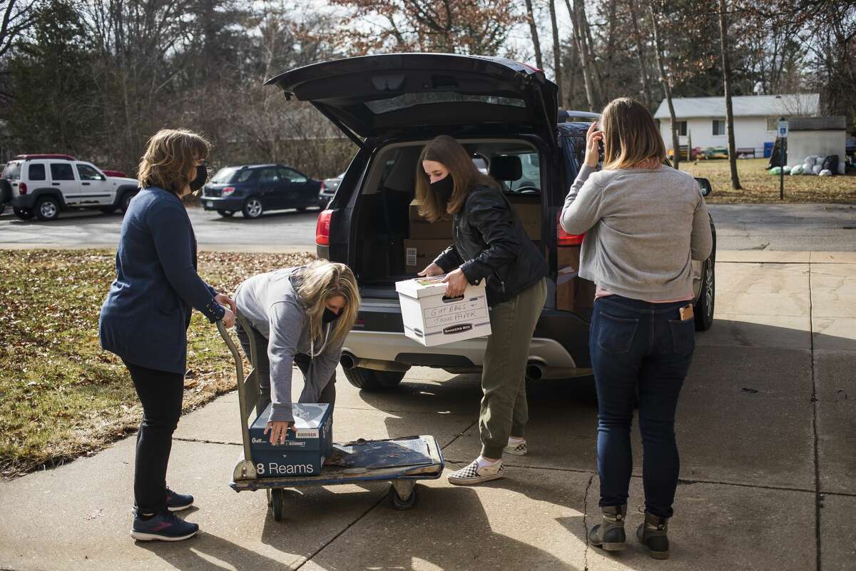 Tracy Robinson of the Salem South Lyon District Library, second from left, and her daughter Cailyn, second from right, load boxes of donated books onto a dolly as Miriam Andrus, Director of the Grace A. Dow Memorial Library, right, and Deanna Schroden, left, stand by before organizing the books in the library at Windover High School, which was severely damaged in last year's flood, Wednesday, March 24, 2021. (Katy Kildee/kkildee@mdn.net)
