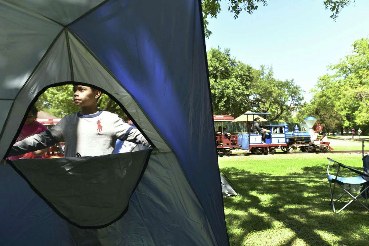 Saint Gonzales helps set up at tent for his family at Brackenridge Park as the San Antonio Zoo Eagle train travels by on Saturday, April 20, 2019. Many families traditionally camp out at the park Easter weekend.