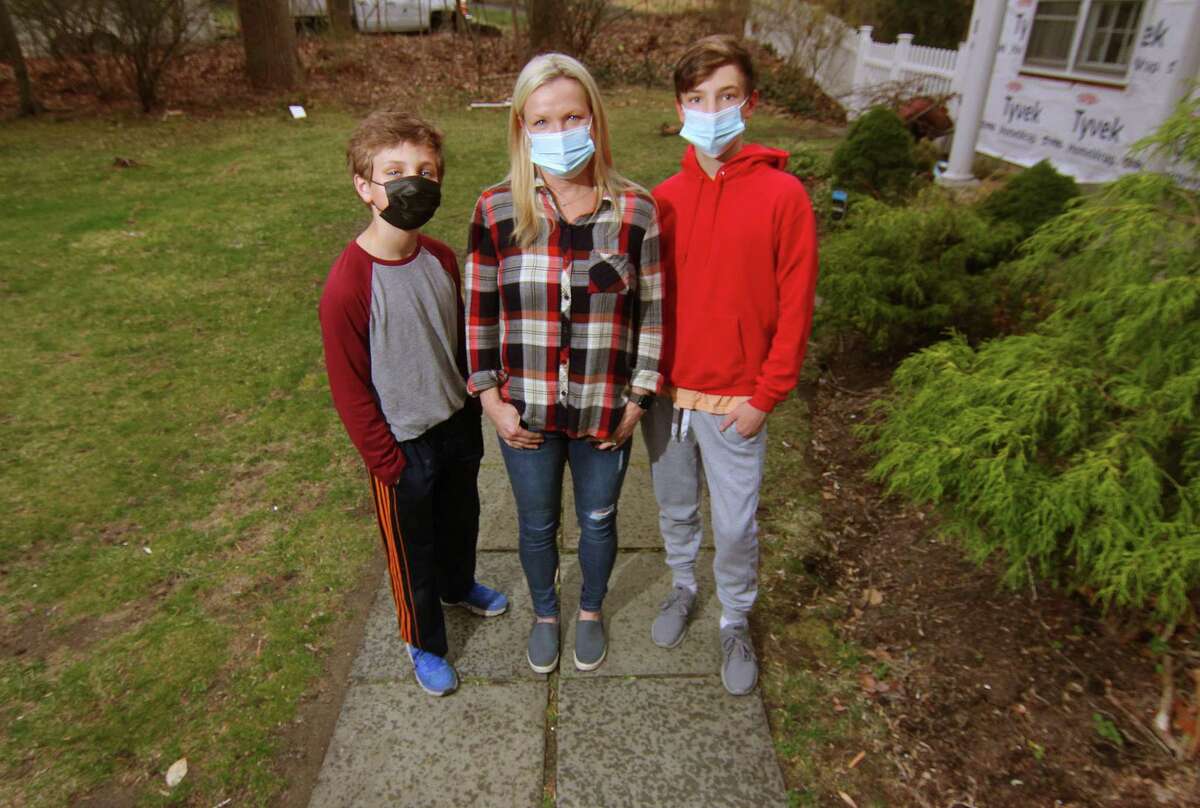 Kristina Gregory, center, poses with her sons Nathan, 12, left, and Peter, 15, at their home in Darien, Conn., on Wednesday March 31, 2021. Gregory is supportive of getting her sons vaccinated when they are eligible after having a tough journey with COVID a year ago that continues to have lingering effects.