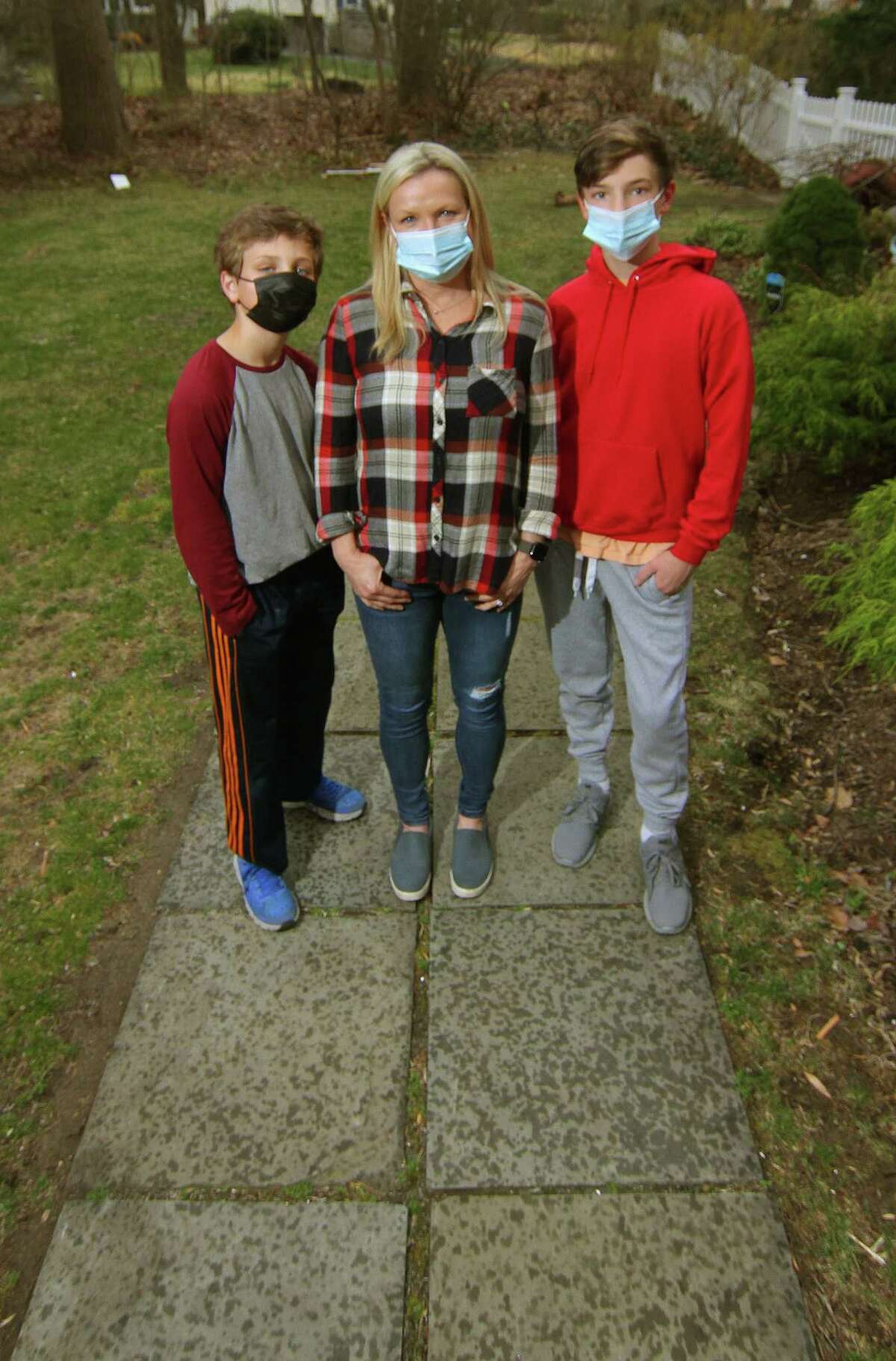 Kristina Gregory, center, poses with her sons Nathan, 12, left, and Peter, 15, at their home in Darien, Conn., on Wednesday March 31, 2021. Gregory is supportive of getting her sons vaccinated when they are eligible after having a tough journey with COVID a year ago that continues to have lingering effects.