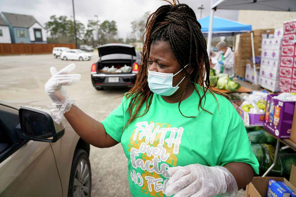 Volunteer Shronda Williams directs a vehicle at the Community of Faith's food pantry program Wednesday, March 10, 2021 in Houston. She is experiencing long term unemployment during the COVID-19 pandemic.