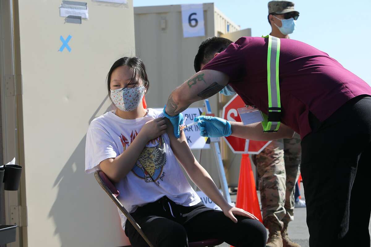 Valerie Lee of Contra Costa is inoculated by a National Guard medic at Hurricane Harbor Concord on Wedneday, March 31, 2021, in Concord, Calif. The new, drive-through COVID-19 vaccination site is available in Concord.
