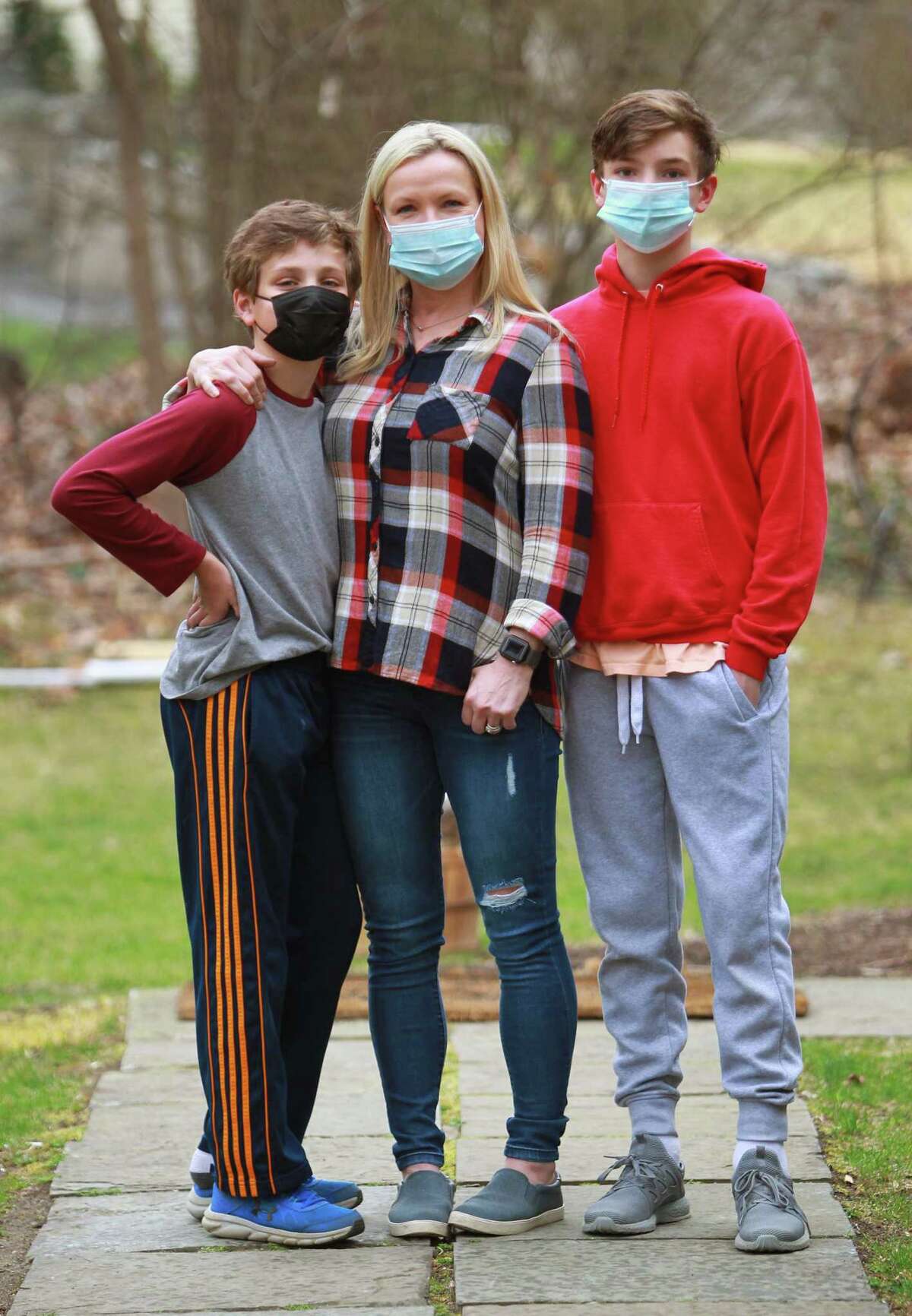 Kristina Gregory, center, poses with her sons Nathan, 12, left, and Peter, 15, at their home in Darien, Conn., on Wednesday March 31, 2021. Gregory is supportive of getting her sons vaccinated when they are eligible after having a tough journey with COVID a year ago that continues to have lingering effects.