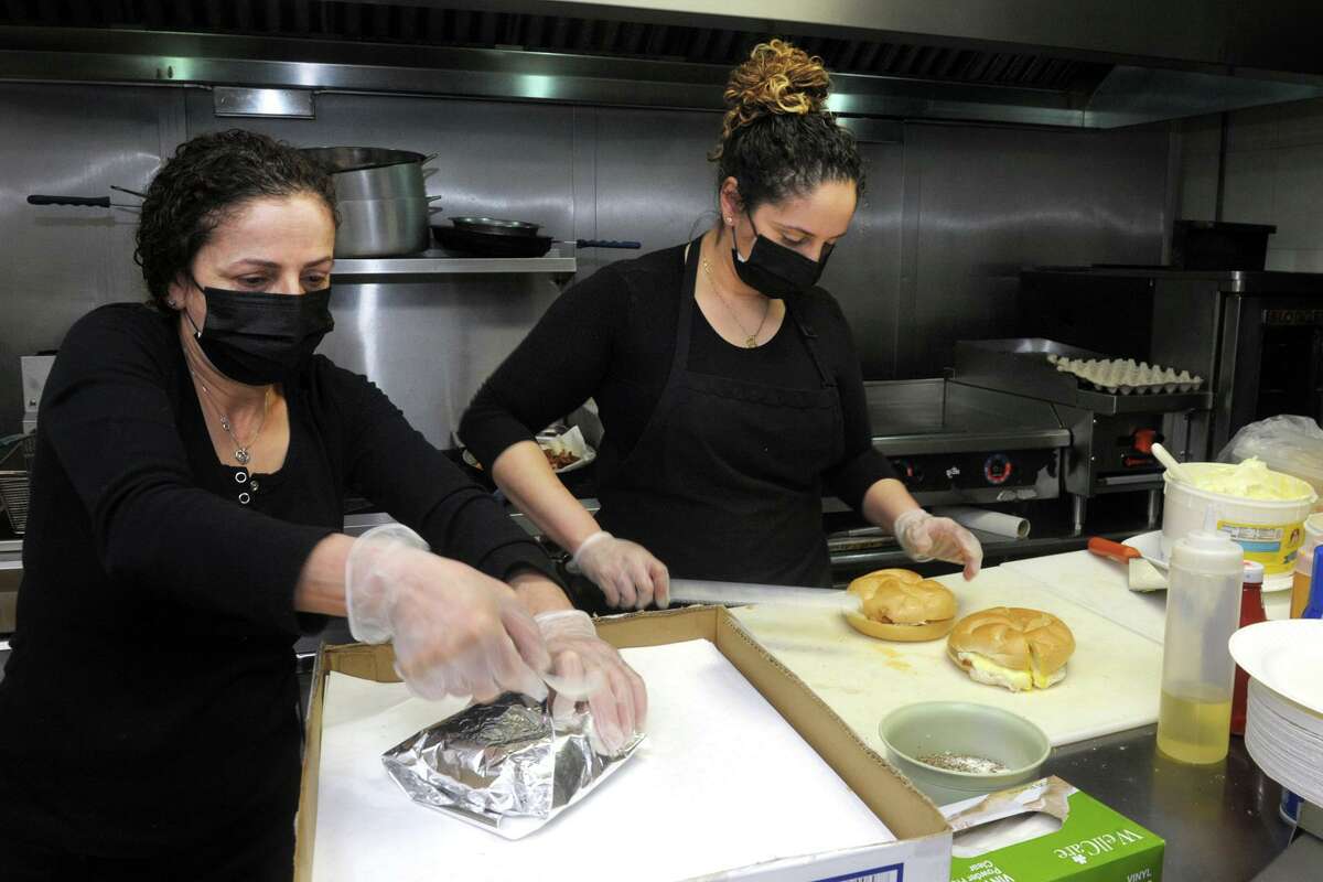 Owners Amal Johnston, left, and her daughter Dalia Ghossaini prepare breakfast sandwiches for the morning rush at Brooklawn Grocery & Deli, in Bridgeport, Conn. March 31, 2021. On Easter, the deli will be serving $1,500 worth of free breakfast sandwiches to whomever shows up.
