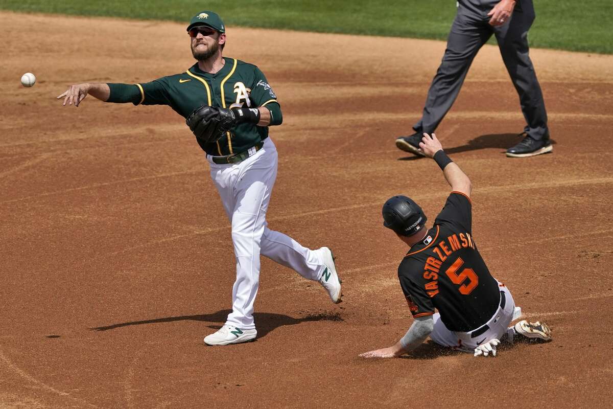 Oakland Athletics' Jed Lowrie forces out San Francisco Giants' Mike Yastrzemski but can't turn a double play during the first inning of a spring training baseball game on March 29, 2021.