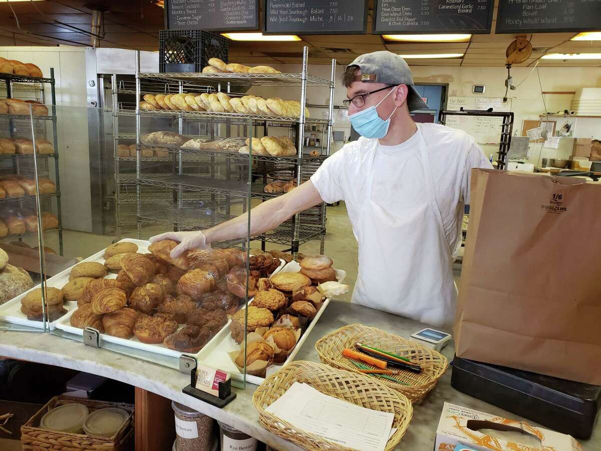 At Wave Hill Breads in Norwalk, a baker with a flour-dusted apron stops working and comes to the counter to serve.