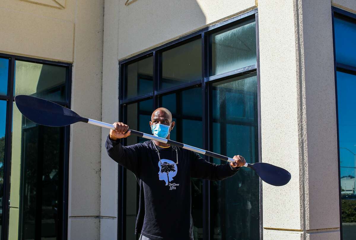 Abu Baker, a local leader with Outdoor Afro, demonstrates how to use a paddle in front of kayaking participants outside John Henry High School in Richmond.