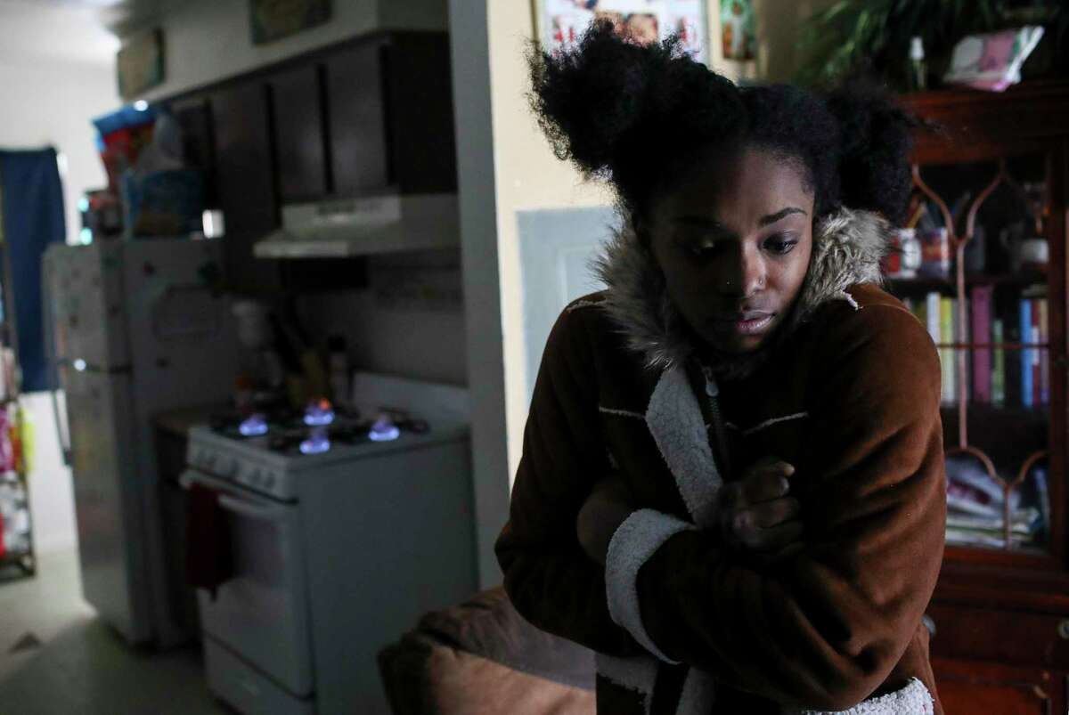 Shanice Ardion holds her jacket tight in her home as her stove burns in the background Tuesday, Feb. 16, 2021, at Cuney Homes in Houston. She said the stove was their only source of heat since their power has been out since yesterday.
