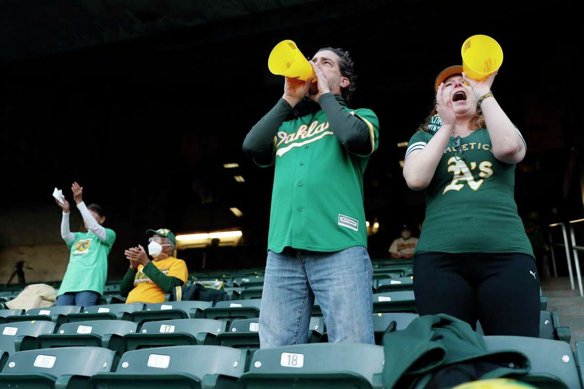 A's fans Mike Manolas and Anne Allen cheer as Oakland Athletics play Houston Astros in season opener at Oakland Coliseum in Oakland, Calif., on Thursday, April 1, 2021.