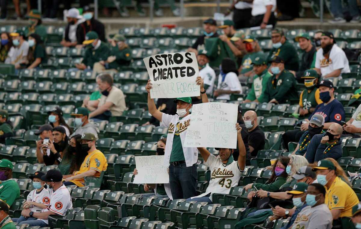 OAKLAND, CALIFORNIA - APRIL 01: Oakland Athletics fans hold up signs about the Houston Astros cheating during their Opening Day game at RingCentral Coliseum on April 01, 2021 in Oakland, California.