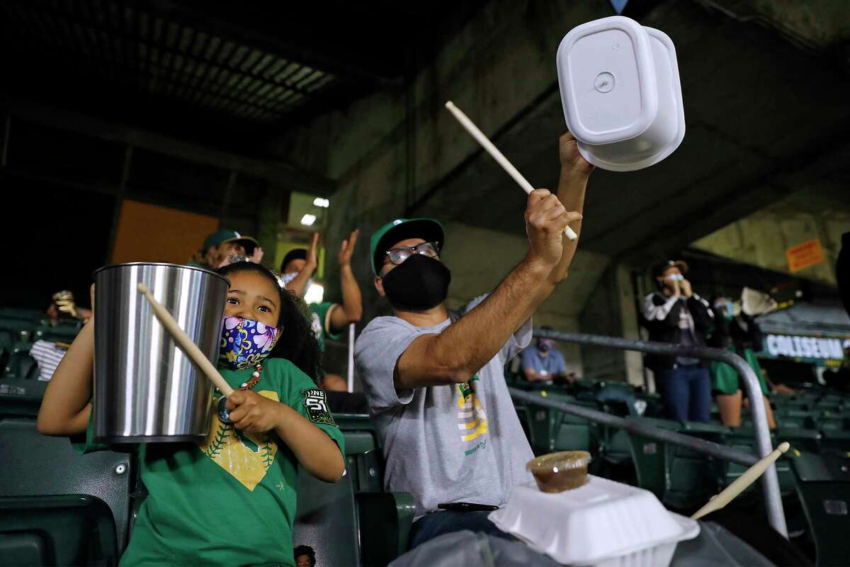 Sofia Gonzalez, 5, and her father, Anthony of Oakland beat on garbage cans after Houston Astros' Jose Altuve was retired on a diving catch by Oakland Athletics' Chad Pinder in 5th inning of season opener at Oakland Coliseum in Oakland, Calif., on Thursday, April 1, 2021.