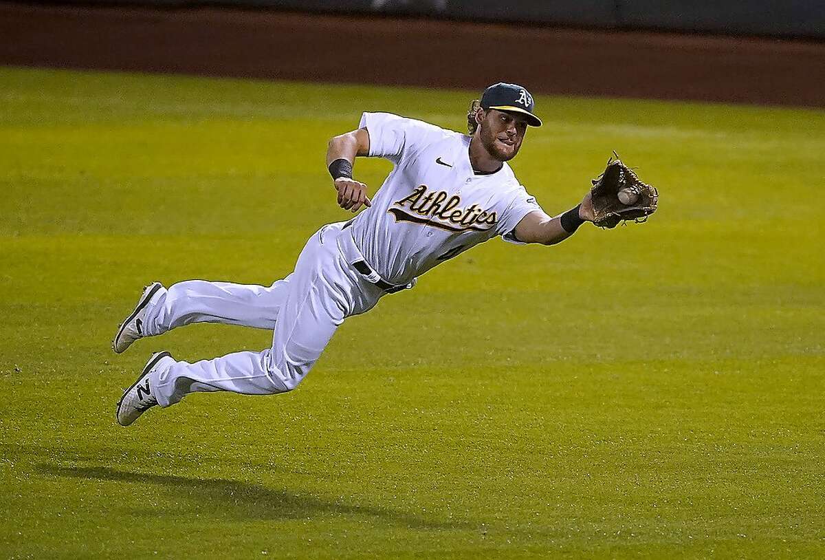 Oakland Athletics right fielder Chad Pinder makes a diving catch on a hit by Houston Astros' Jose Altuve during the fifth inning of an opening day baseball game in Oakland, Calif., Thursday, April 1, 2021. (AP Photo/Tony Avelar)