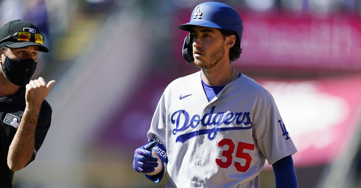 Los Angeles Dodgers' Cody Bellinger reacts after being called out after what he thought was a home run in the third inning of a baseball game against the Colorado Rockies Thursday, April 1, 2021, in Denver. Bellinger lined what appeared to be a two-run homer to left-center. The ball hit off the glove of outfielder Raimel Tapia and bounded over the fence. Justin Turner was on first base at the time and believing the ball was caught, retreated back to the bag. Bellinger passed Turner in the confusion and the umpires ruled Bellinger out. (AP Photo/David Zalubowski)
