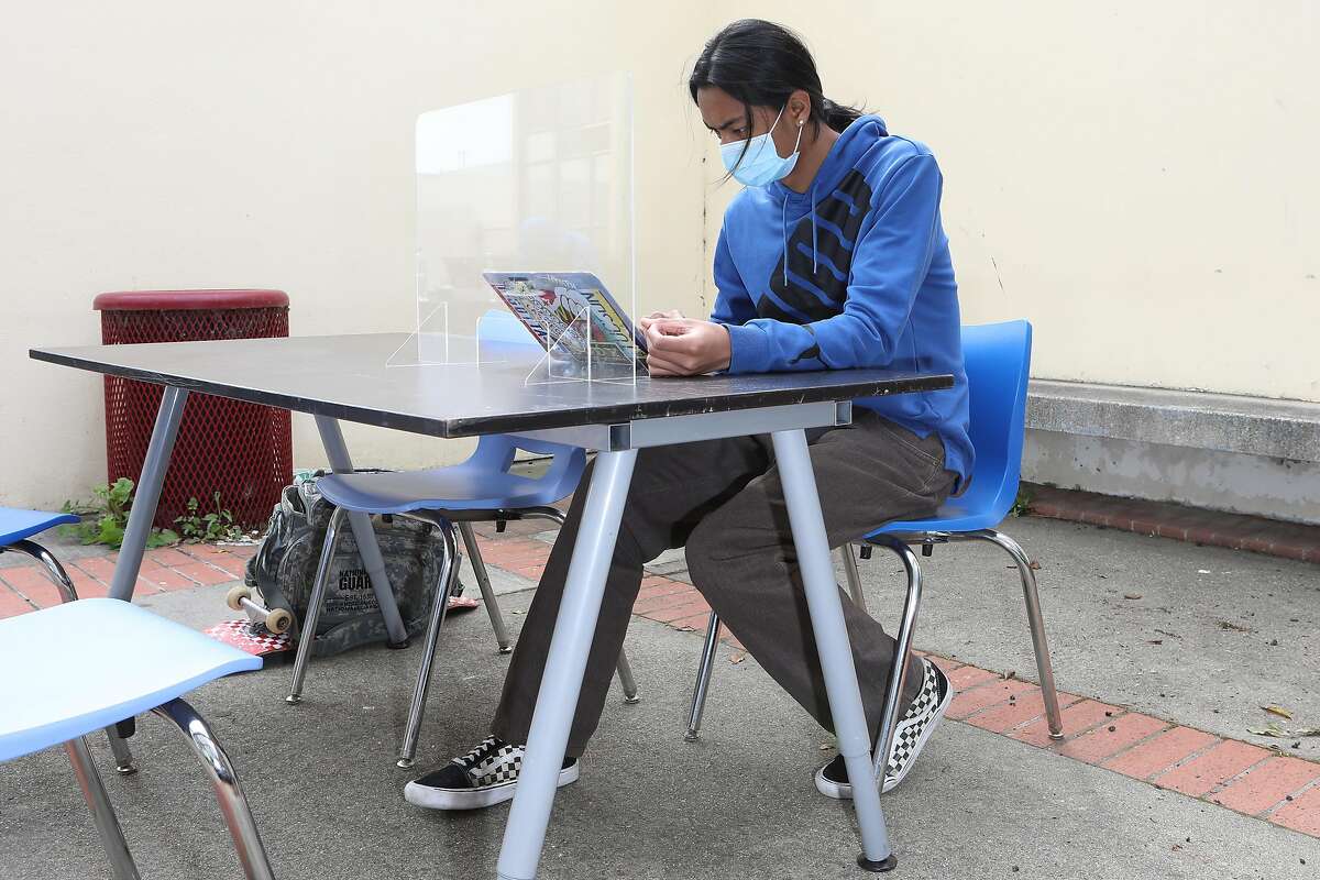 Andrew Taate, a freshman, works at a desk in a courtyard at Thurgood Marshall High School in San Francisco. Teachers meet with students outside the school on Wednesdays to provide them with a range of support.
